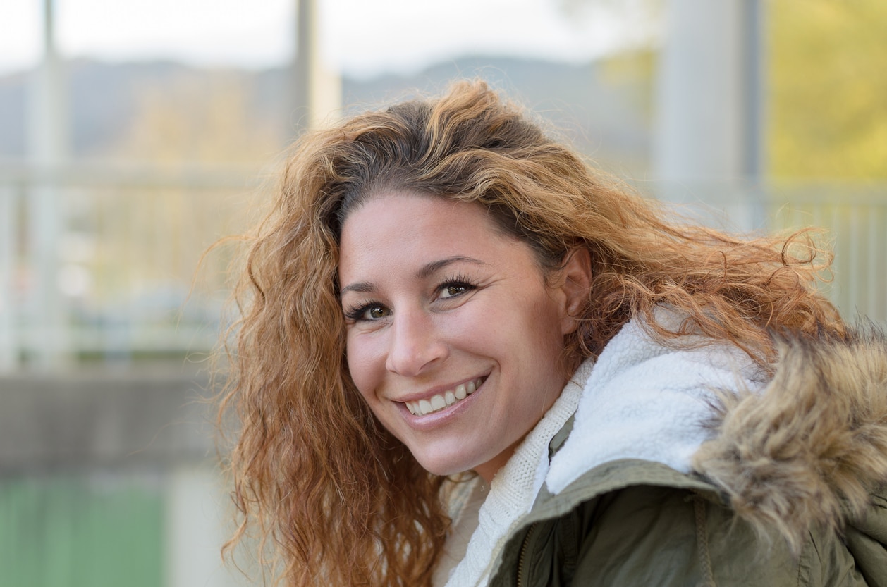 woman with curls is laughing at the camera