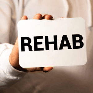 man in white shirt holding white plaque saying rehab